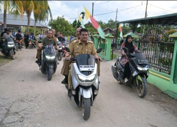 metrodeli/istimewa TINJAU : Gubsu M Bobby Afif Nasution berboncengan dengan Bupati Langkat Syah Afandin bersama sejumlah OPD meninjau langsung Posyandu Pembantu (Postu) serta berdialog dengan masyarakat Desa Pulau Kampai, Kecamatan Pangkalan Susu, Kabupaten Langkat, saat melakukan kunjungan kerja, Senin 21 Juli 2025.